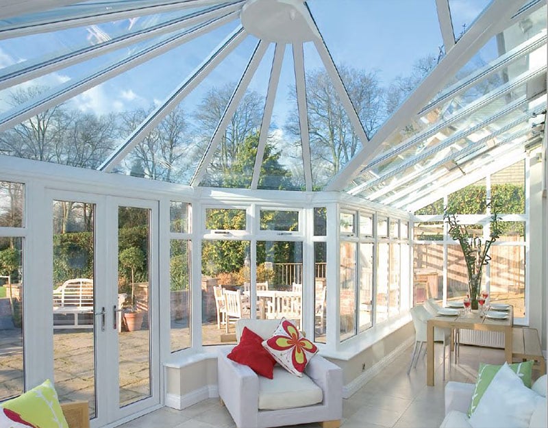 View of white conservatory from the inside of a home. This room is cream with marble floor. The view through the windows is of a beautiful garden in Bristol.